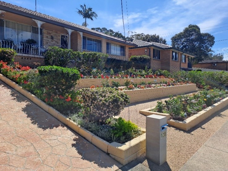 A stunning multi-level garden by Shirley Hunter from Greystanes, a finalist in the 2024 Sydney Royal Spring Garden Competition, featuring neatly arranged flower beds and vibrant plant life.